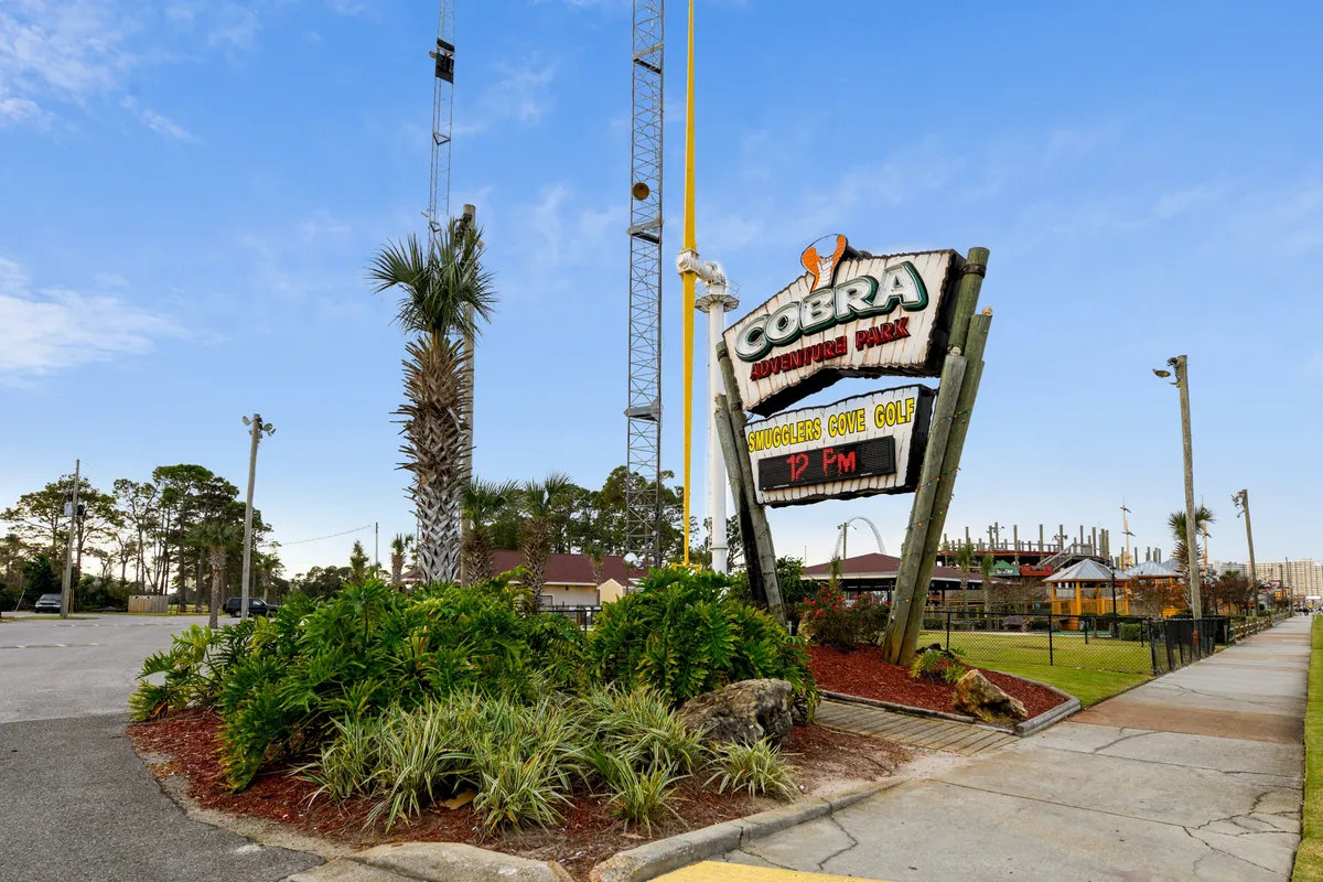 The Cobra Adventure Park sign stands out amid palm trees and tall ride structures, signaling a hub of amusement and adventure. Bright signage and visible rides promise excitement and group fun just outside the resort.