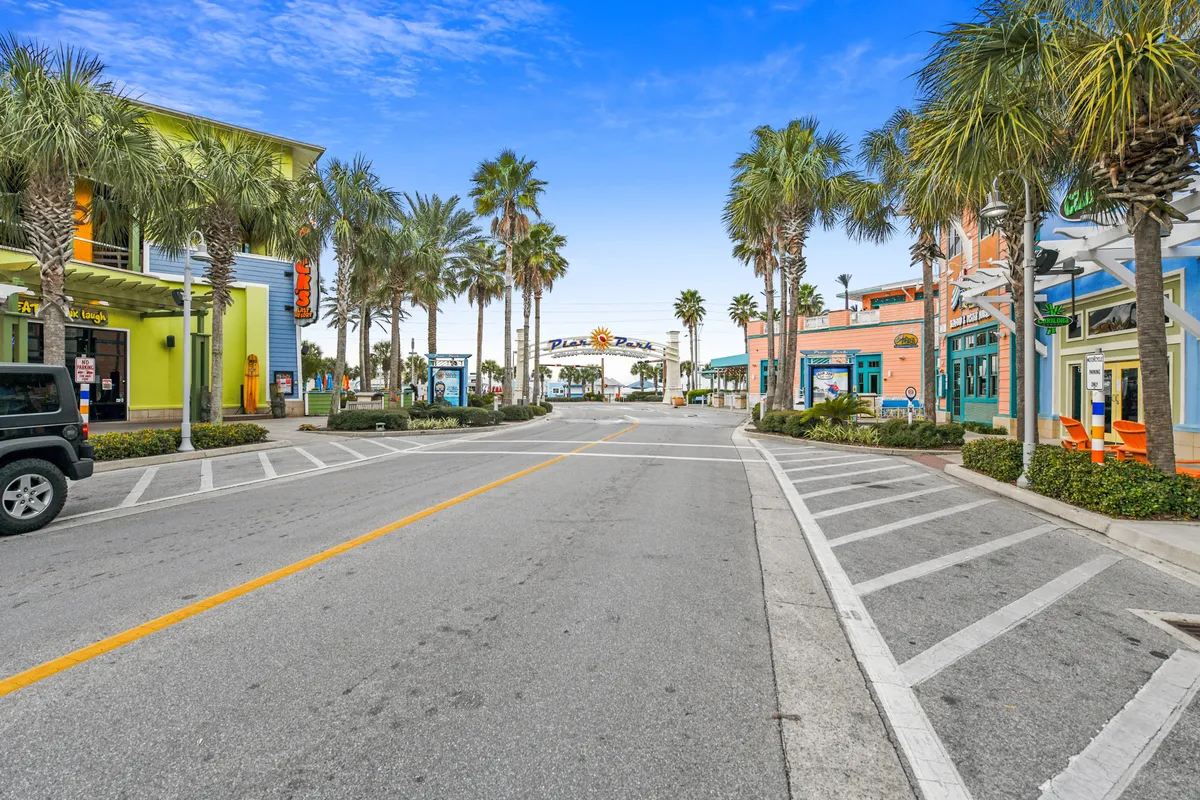 A lively exterior street scene with palm trees, colorful storefronts, and the inviting signage for Plaza Panama at the end of the street. The area is designed for shopping, dining, and strolling, embodying the vibrant local culture.